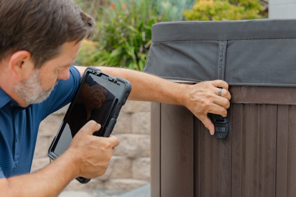 A home inspector is checking the locking system for a hot tub. Safety check for the lid.