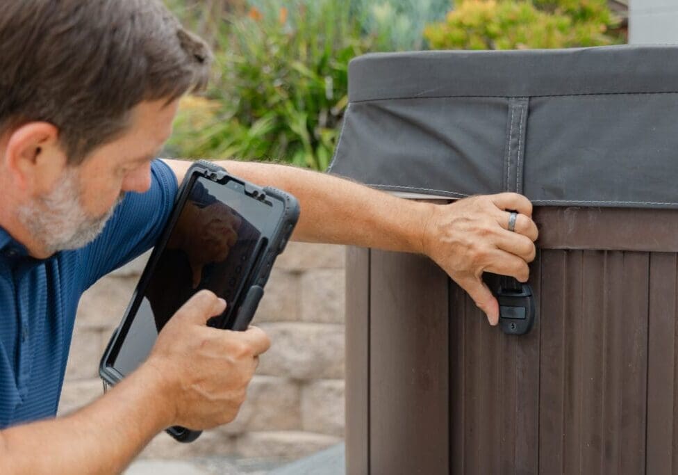 A home inspector is checking the locking system for a hot tub. Safety check for the lid.